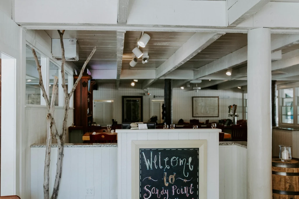Chalkboard sign "Welcome to Sandy Point" in a bright coastal restaurant.