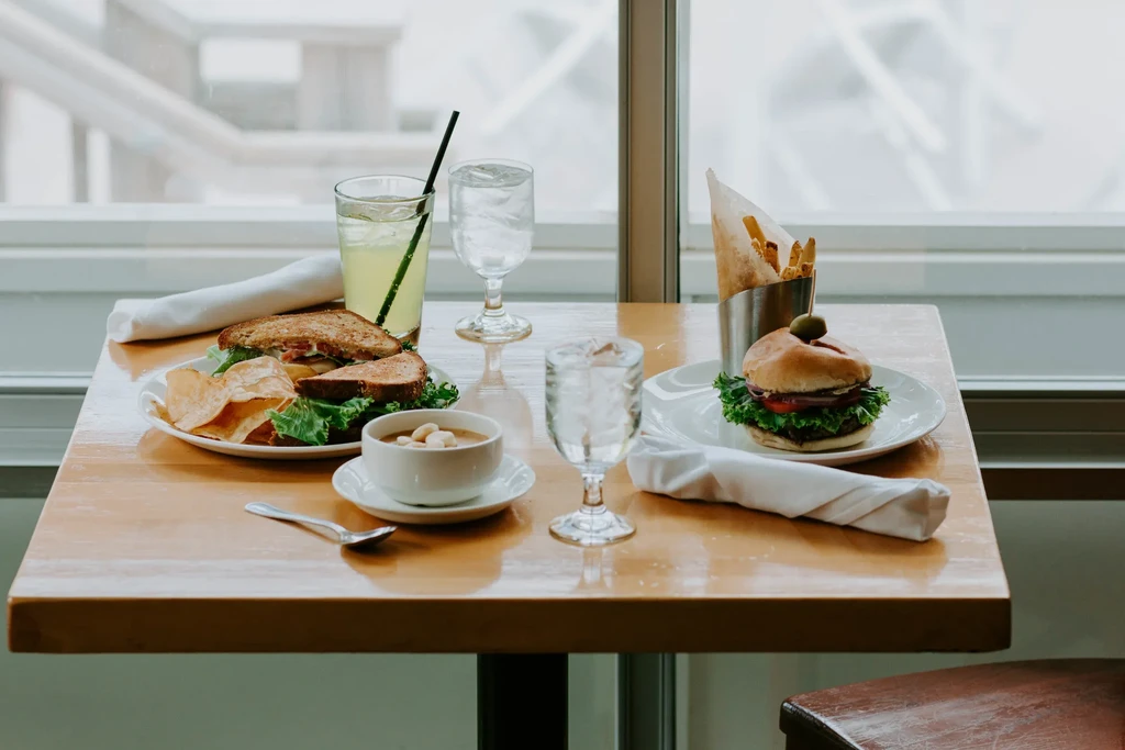 Two restaurant meals: toasted sandwich with soup, and a burger with fries.