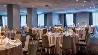 Formal event hall with elegantly set round tables and floral centerpieces.
