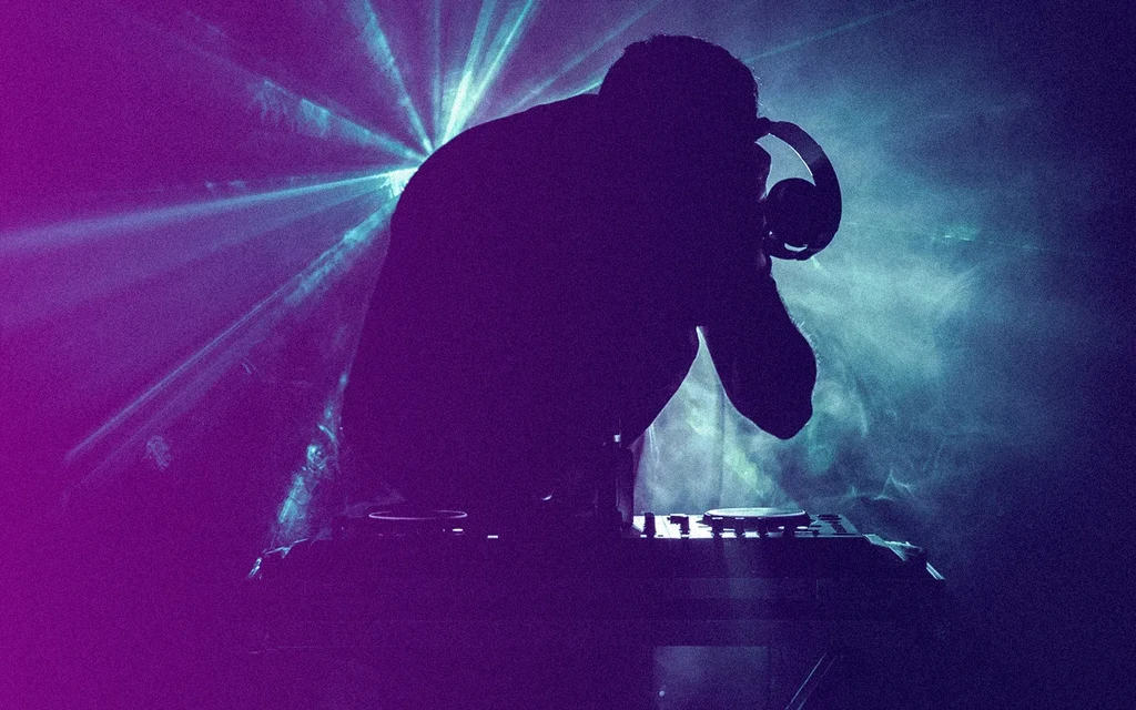 Silhouette of a DJ with headphones against blue and purple lasers.