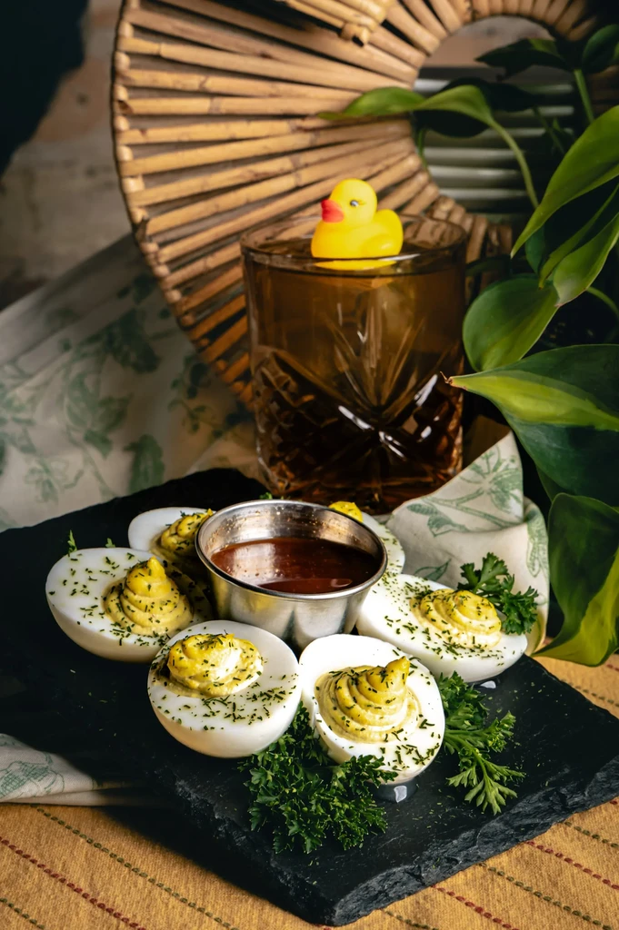 Deviled eggs on slate, next to a cocktail with a rubber duck.