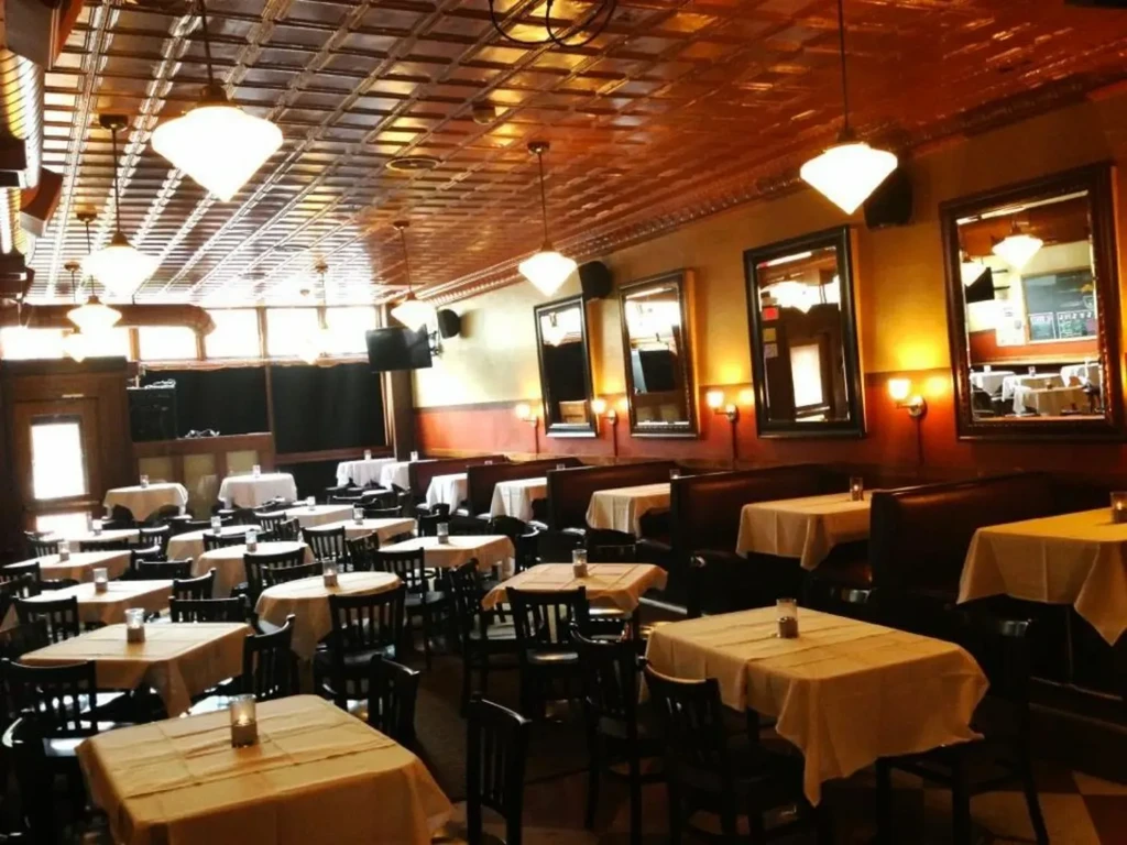 Empty, warm restaurant interior with tables, booths, and pressed tin ceiling.