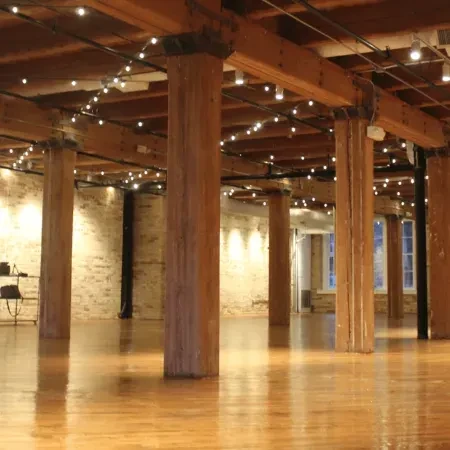Spacious room with thick wooden pillars, exposed beams, and string lights.