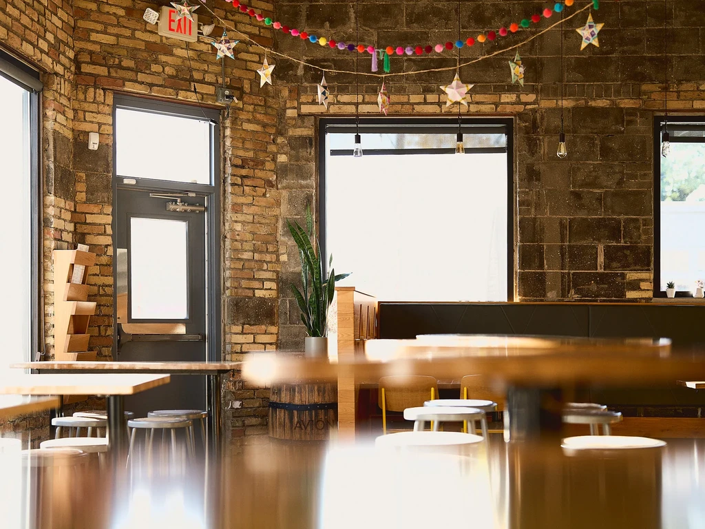 Brightly lit restaurant with exposed brick, colorful decor, and wooden furniture.