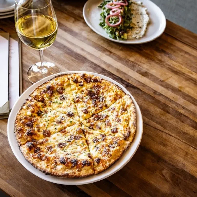 Overhead view of pizza, wine, and salad on a rustic wooden table.