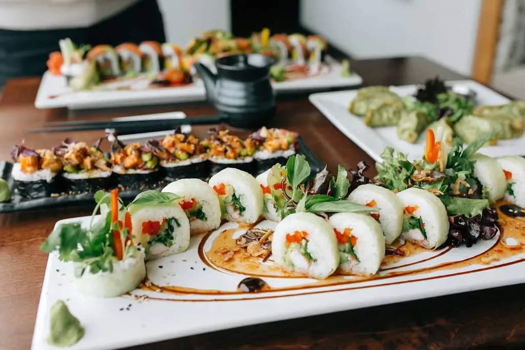 Artfully presented maki, sushi, and green dumplings on a dark restaurant table.