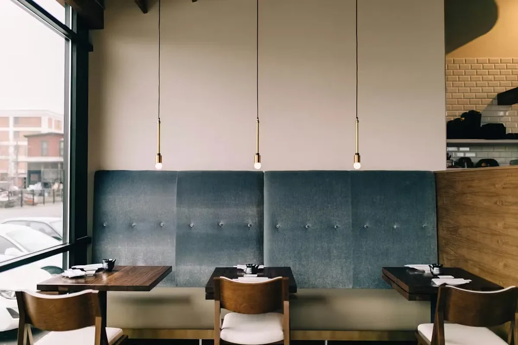 Contemporary restaurant dining with teal booth, wooden tables, urban view.