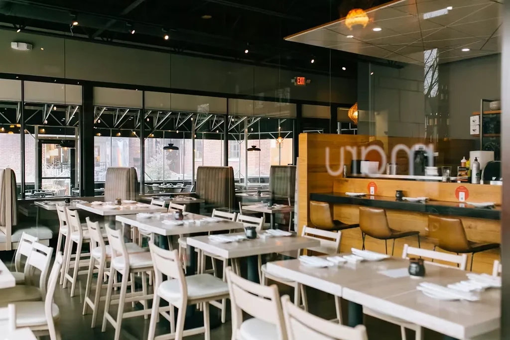 Well-lit, modern restaurant interior with empty dining area, bar, and city view.