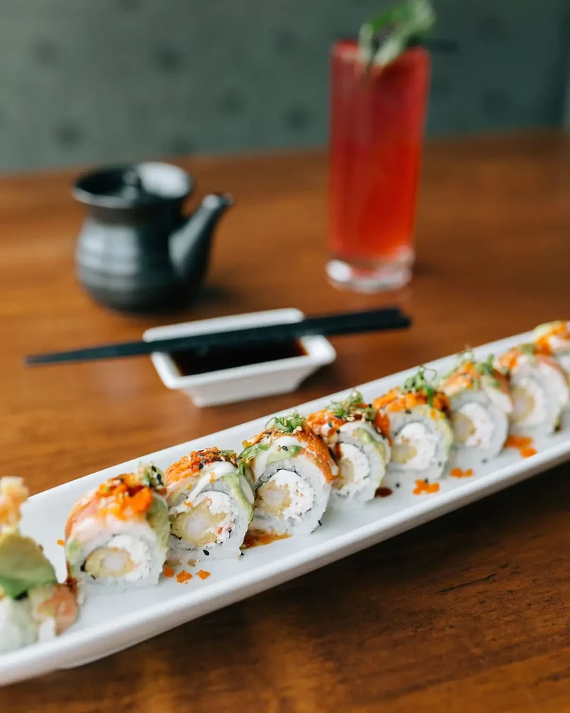 White plate of tempura shrimp sushi rolls with colorful toppings.