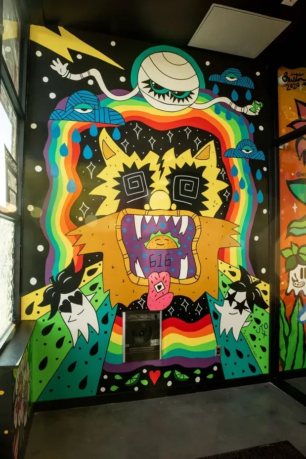 Vibrant mural: yellow monster, spiral eyes, reveals smiling taco, '616'.