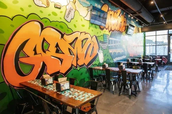 Vibrant restaurant dining room with colorful graffiti murals and industrial decor.