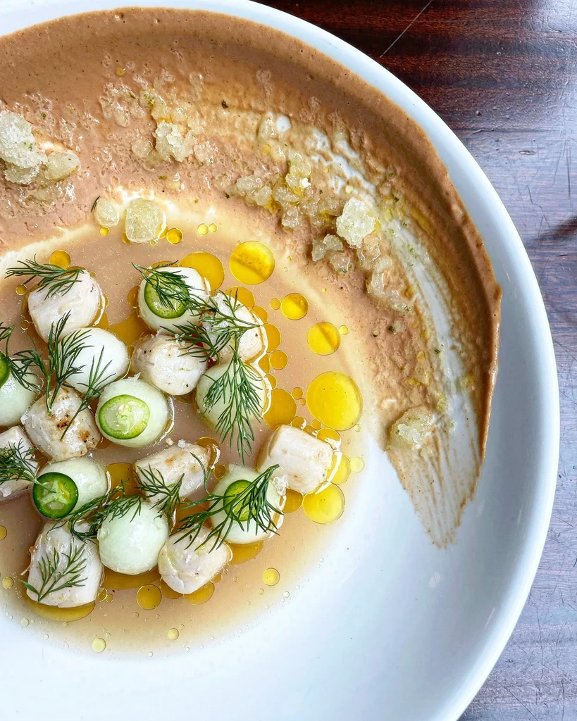 Artfully plated white seafood, green chili, dill, and golden oil.