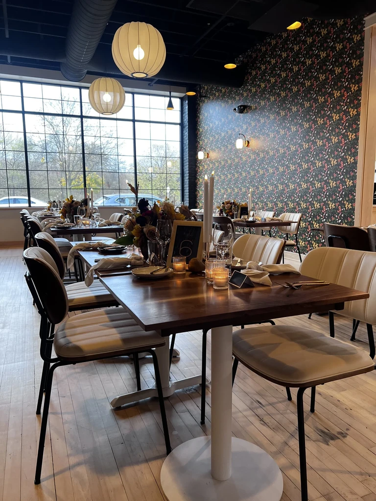 Empty modern dining room with autumn table settings, industrial windows, and lanterns.