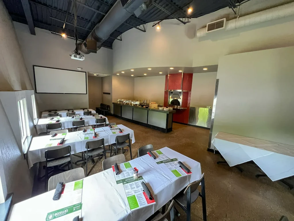 Industrial restaurant interior with set tables, buffet, and red-tiled pizza oven.