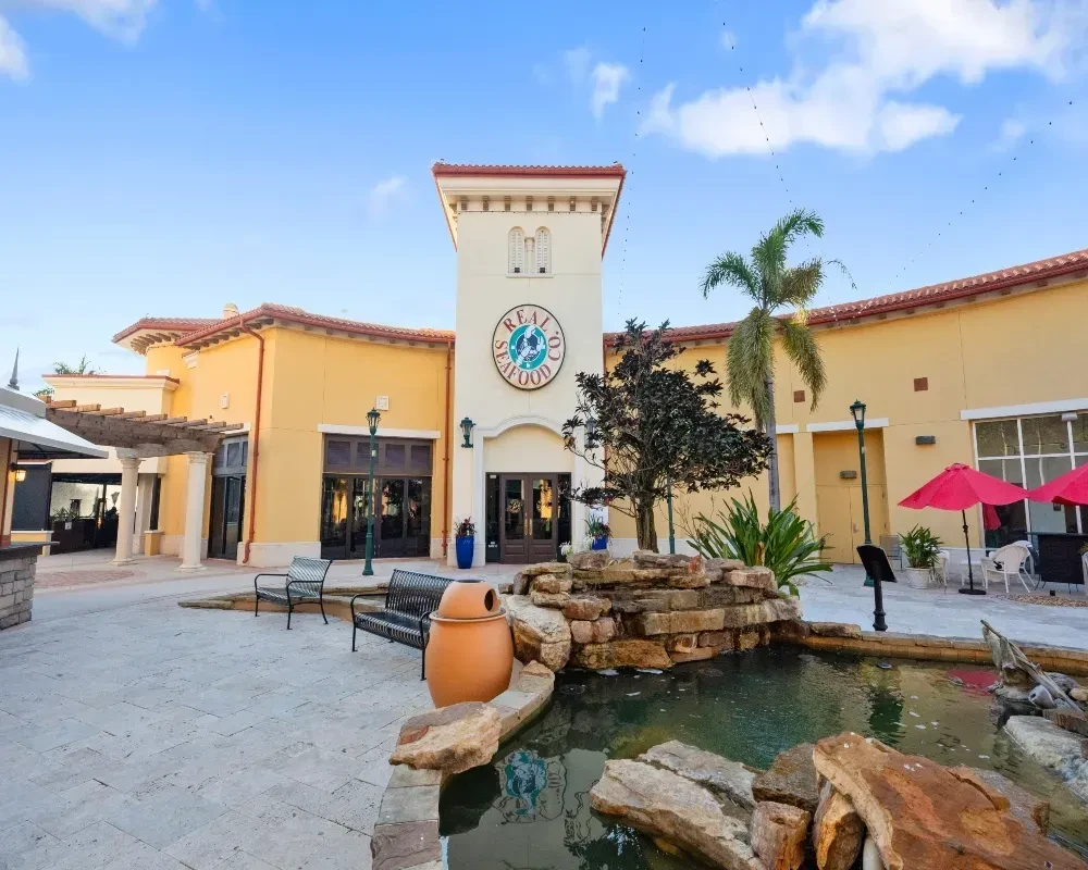 Mediterranean-style Real Co. Seafood restaurant with outdoor seating and fountain.