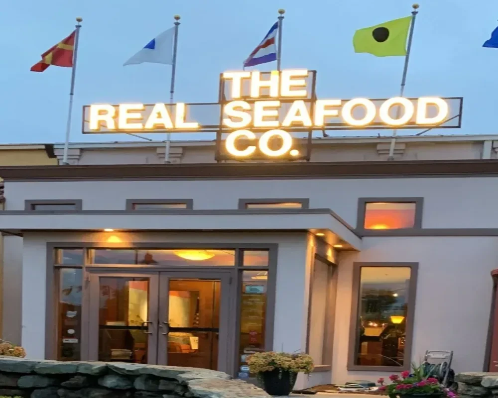 Illuminated THE REAL SEAFOOD CO. restaurant exterior with four maritime signal flags.