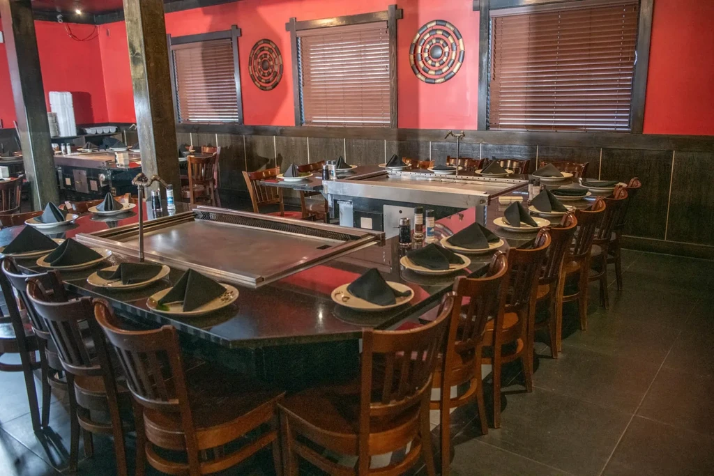 Empty hibachi restaurant interior with octagonal table, griddle, and place settings.