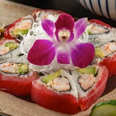 Red tuna, shrimp, avocado sushi rolls garnished with a purple orchid.