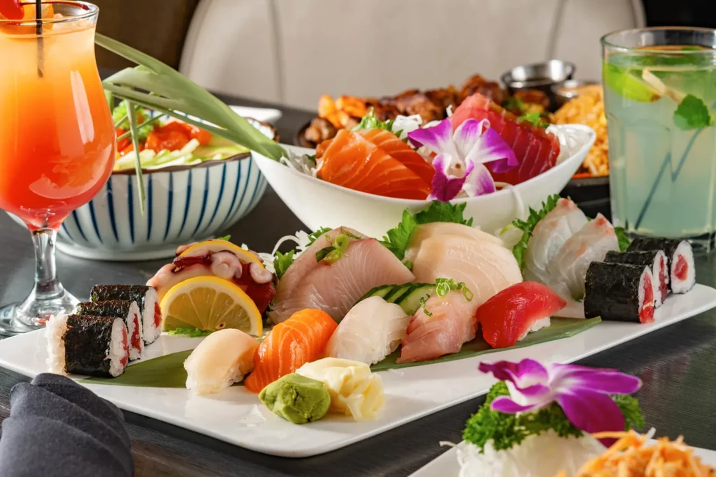 Sushi, sashimi, and maki rolls artfully arranged with a cocktail.