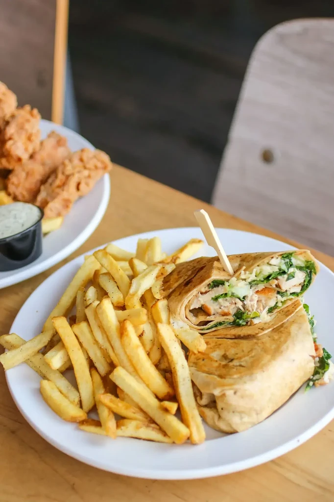 Meal with a sliced wrap, french fries, and chicken tenders.