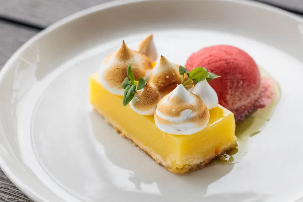 Lemon meringue bar with toasted meringue, red sorbet, green sauce.