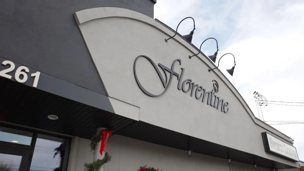 Upward view of Florentine business signage, '261', 'Sports Lounge', holiday garland.
