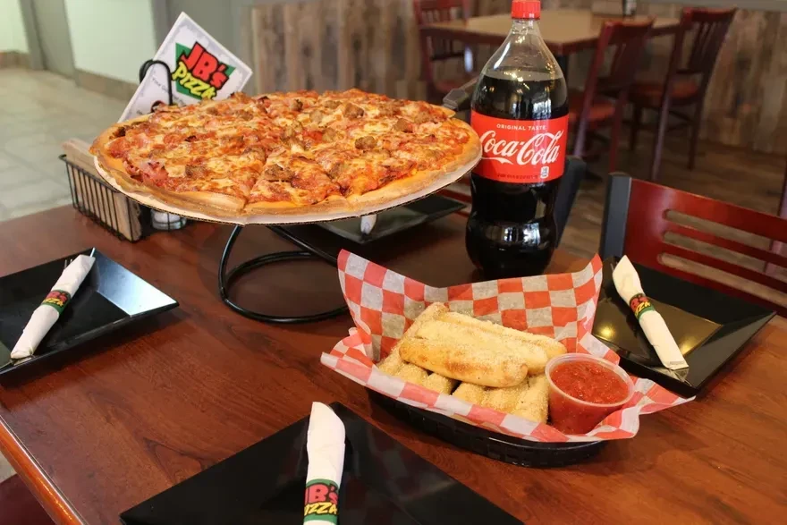 JB's Pizza, breadsticks, marinara, and Coca-Cola on a table.