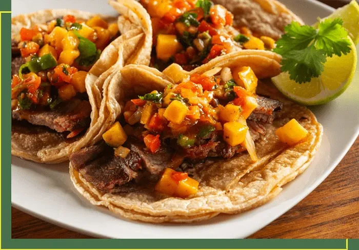 Three tacos filled with seasoned meat and vibrant mango salsa.