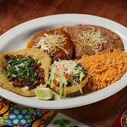 Oval plate filled with various Mexican food: tacos, enchiladas, sopes.