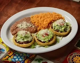 Mexican plate with three sopes, rice, beans, on a colorful placemat.