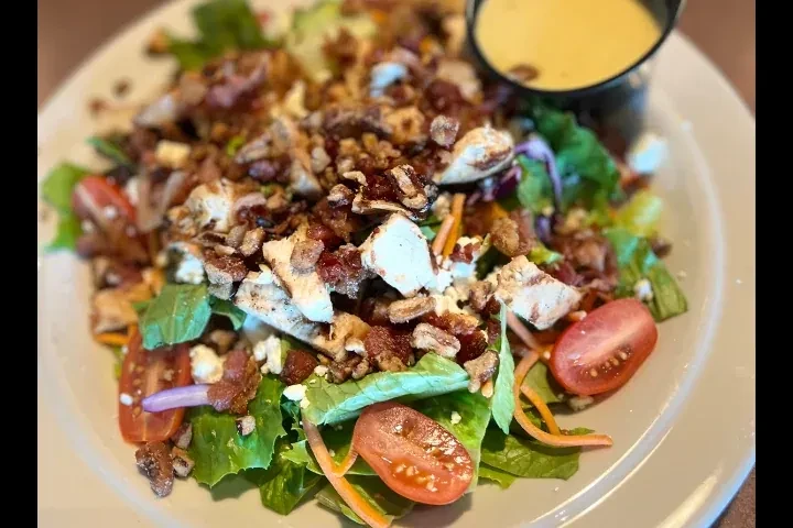 Hearty salad with chicken, bacon, cheese, tomatoes, pecans, and dressing.