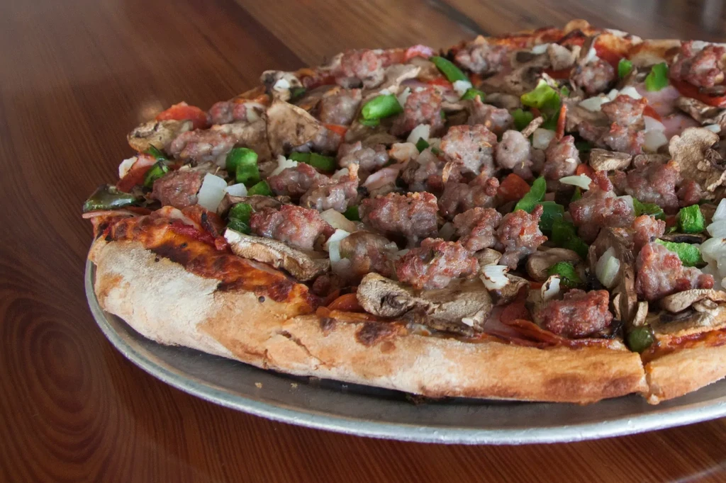 Freshly baked pizza with sausage, mushrooms, peppers, onions, and pepperoni.