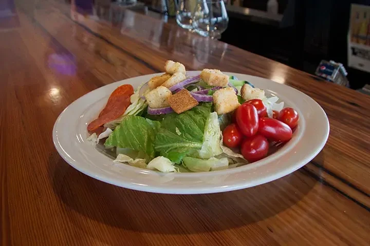 Fresh green salad with tomatoes, croutons, red onions, and cured meat.