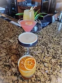 Four distinct cocktails with garnishes on a granite bar counter.