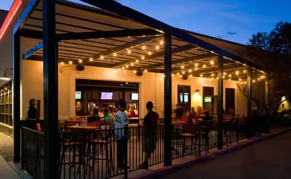 Restaurant patio at dusk with string lights and visible bright interior.