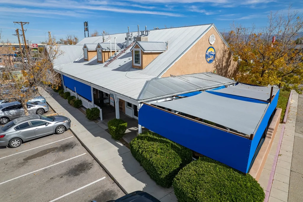 Tan building exterior with blue patio awnings, "Two Spoons" logo, autumn.