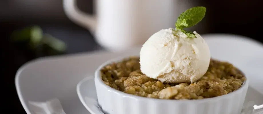 Warm crumble topped with melting vanilla ice cream and a fresh mint leaf.