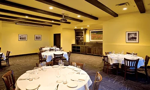 Restaurant dining room with set tables, warm walls, and a projector.
