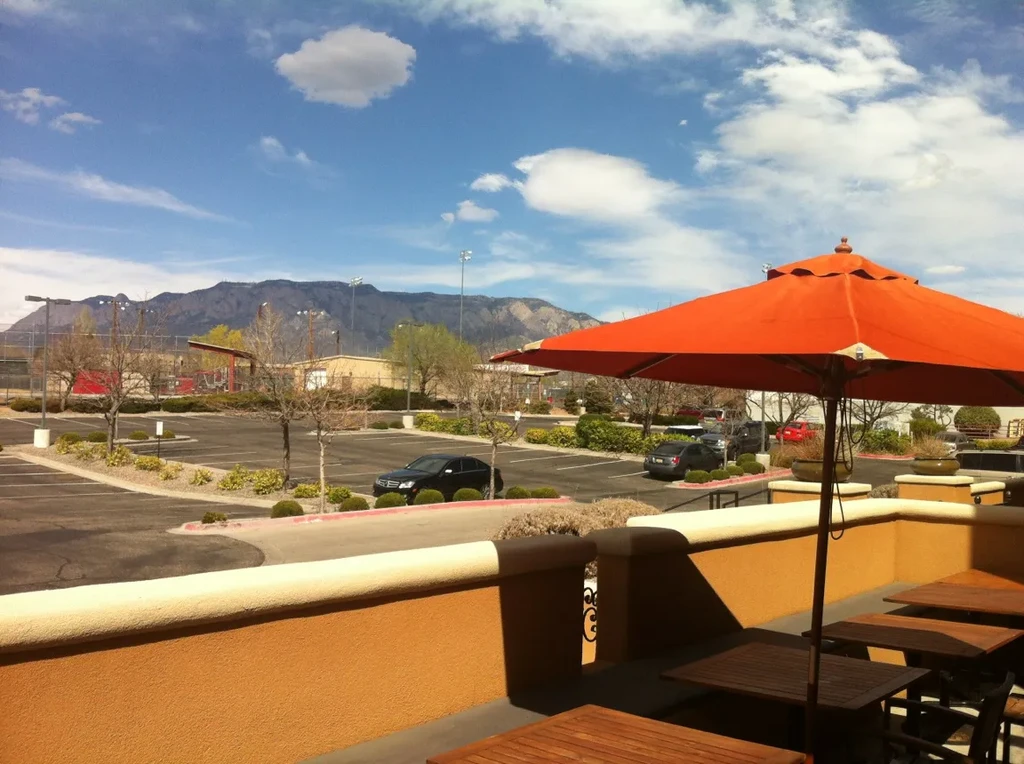 Empty restaurant patio with orange umbrella overlooking mountains.