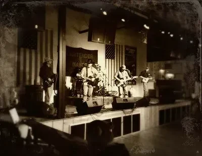 Vintage sepia photo of a band playing on a flag-decorated stage.