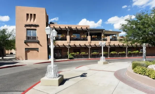 Southwestern-style tan building with multi-level patios and street lamps.