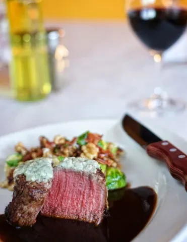Medium-rare steak with blue cheese crust, dark sauce, Brussels sprouts.