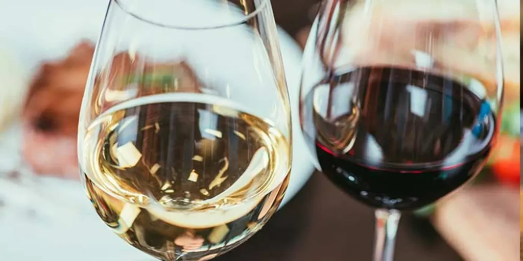 Golden white wine and ruby red wine glasses with blurred background.