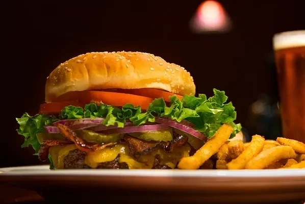 Close-up of a gourmet burger, fries, and beverage on a plate.