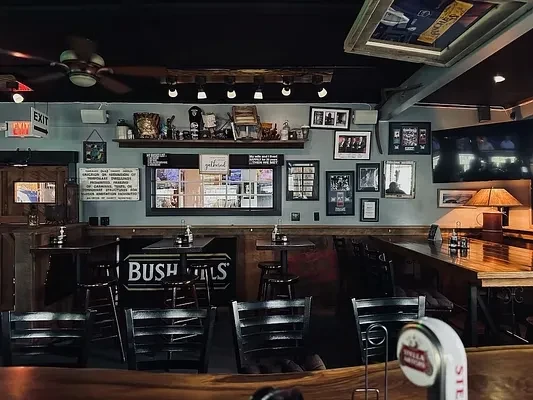 Empty pub interior with a wooden bar, seating, and Bushmills sign.