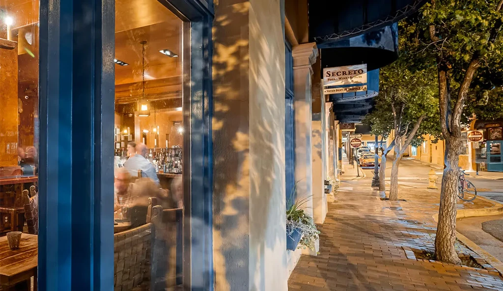Secreto bar exterior at night, with street view and warm interior.