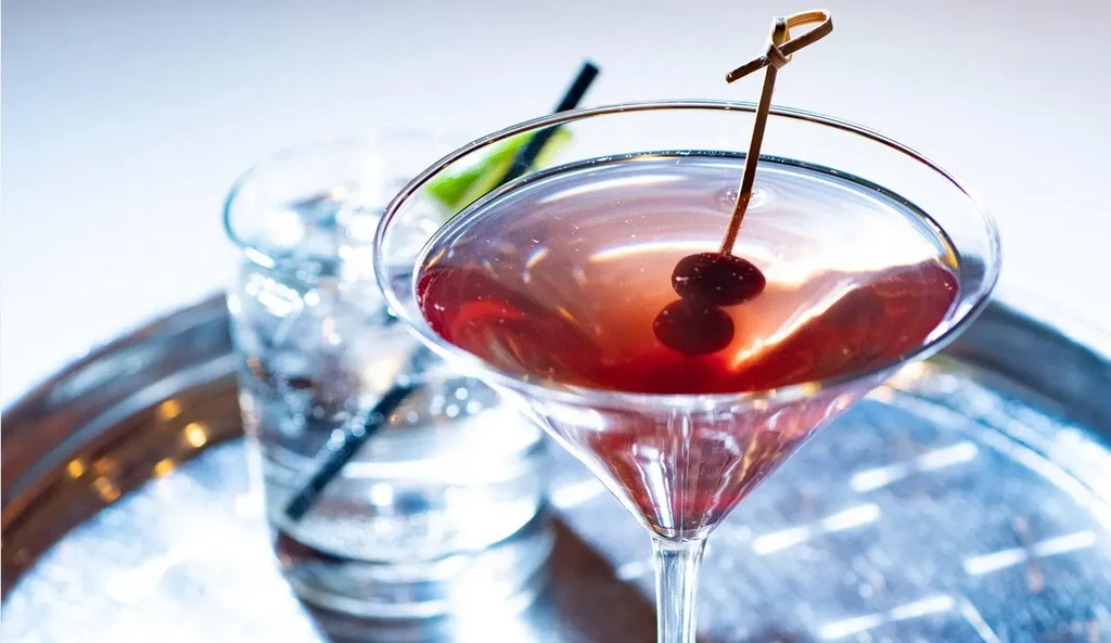 Red martini with cherries, water highball with lime on tray.