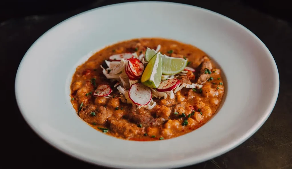Hearty meat and hominy stew garnished with cabbage, radishes, and lime.