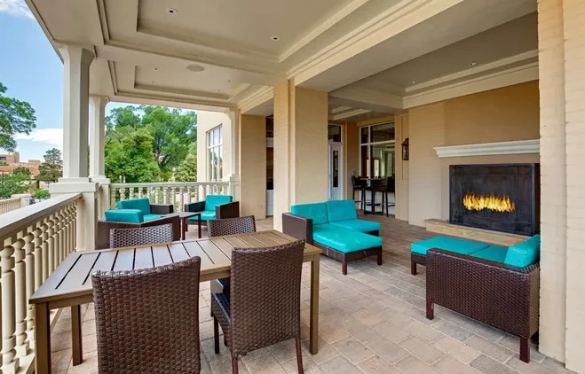 Well-lit outdoor patio with dining, turquoise lounge, fireplace, and city view.