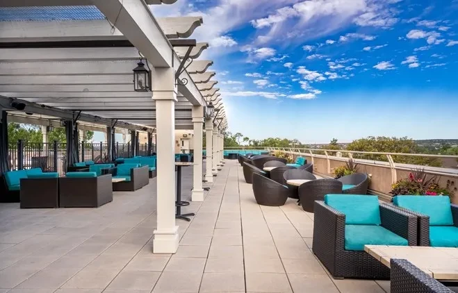 Spacious patio with pergola, turquoise seating, and panoramic sky view.